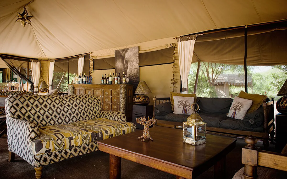 Lounge tent with patterned sofas and a coffee table at Tarangire Nyumba