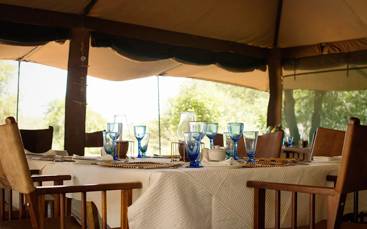 Dining table set with blue glassware in the dining tent at Serengeti Nyumbas
