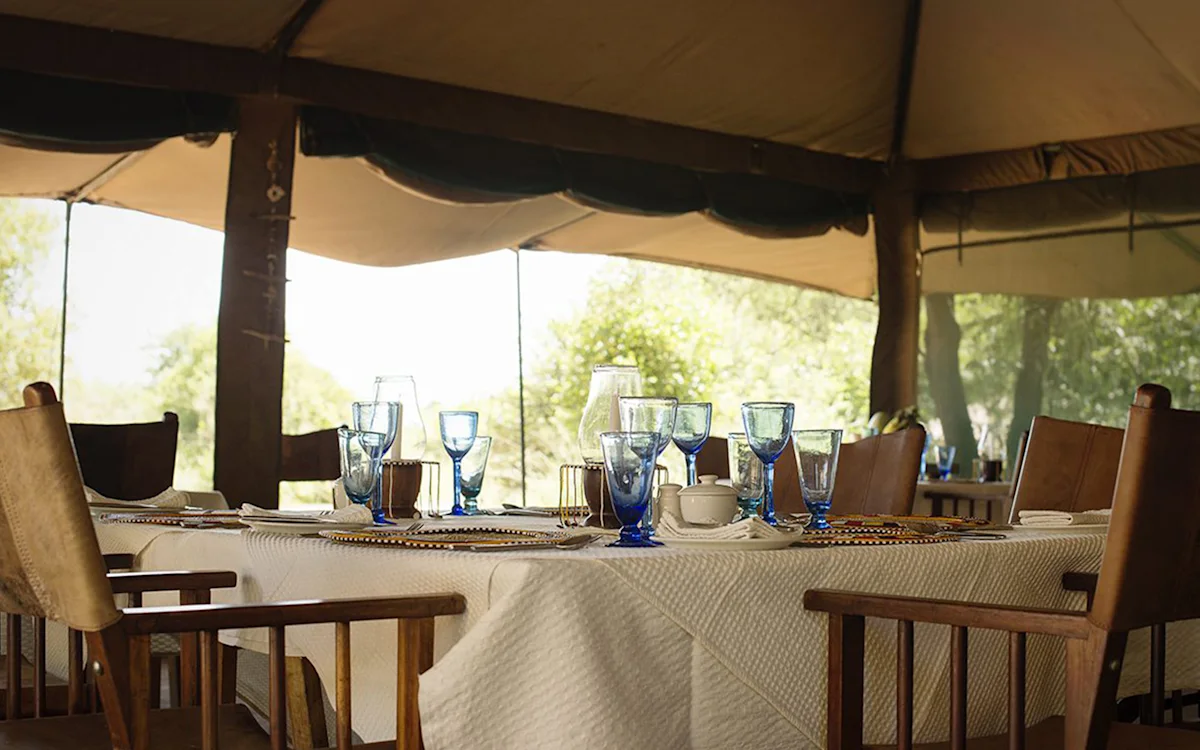 Dining table set with blue glassware in the dining tent at Tarangire Nyumba