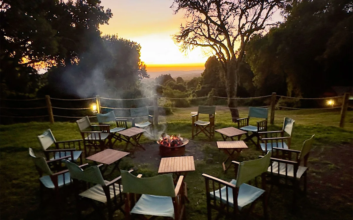 Camp chairs circled around a campfire at sunset at Ngorongoro Nyumba