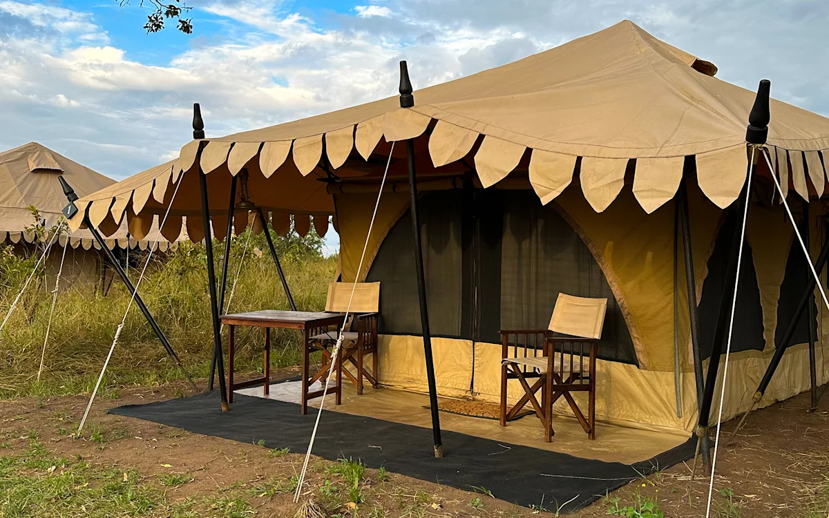 Canvas guest tent with scalloped awning and porch chairs at Serengeti Nyumbas