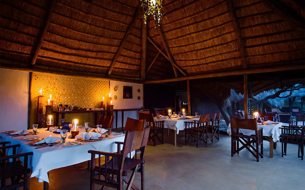Candlelit tables in the thatched dining area at night at Serengeti Nyumbas