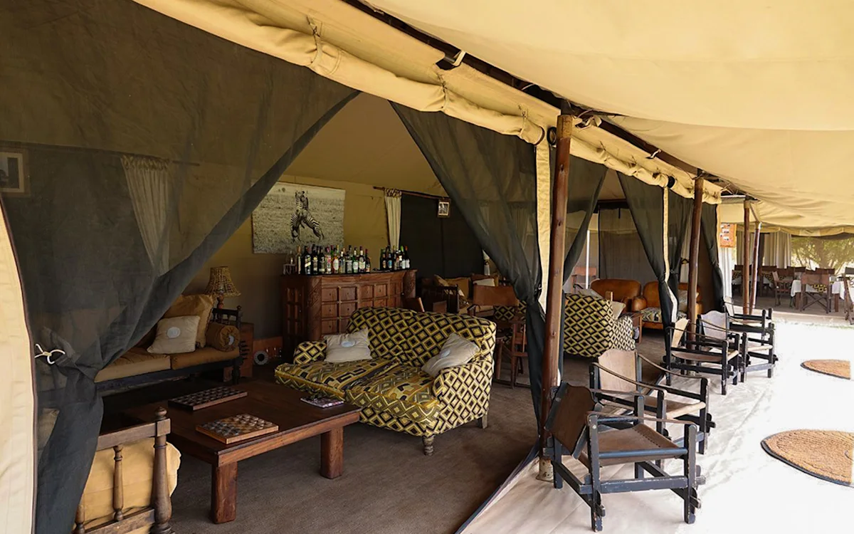 Lounge tent with patterned sofas, a game table and a bar at Serengeti Nyumbas
