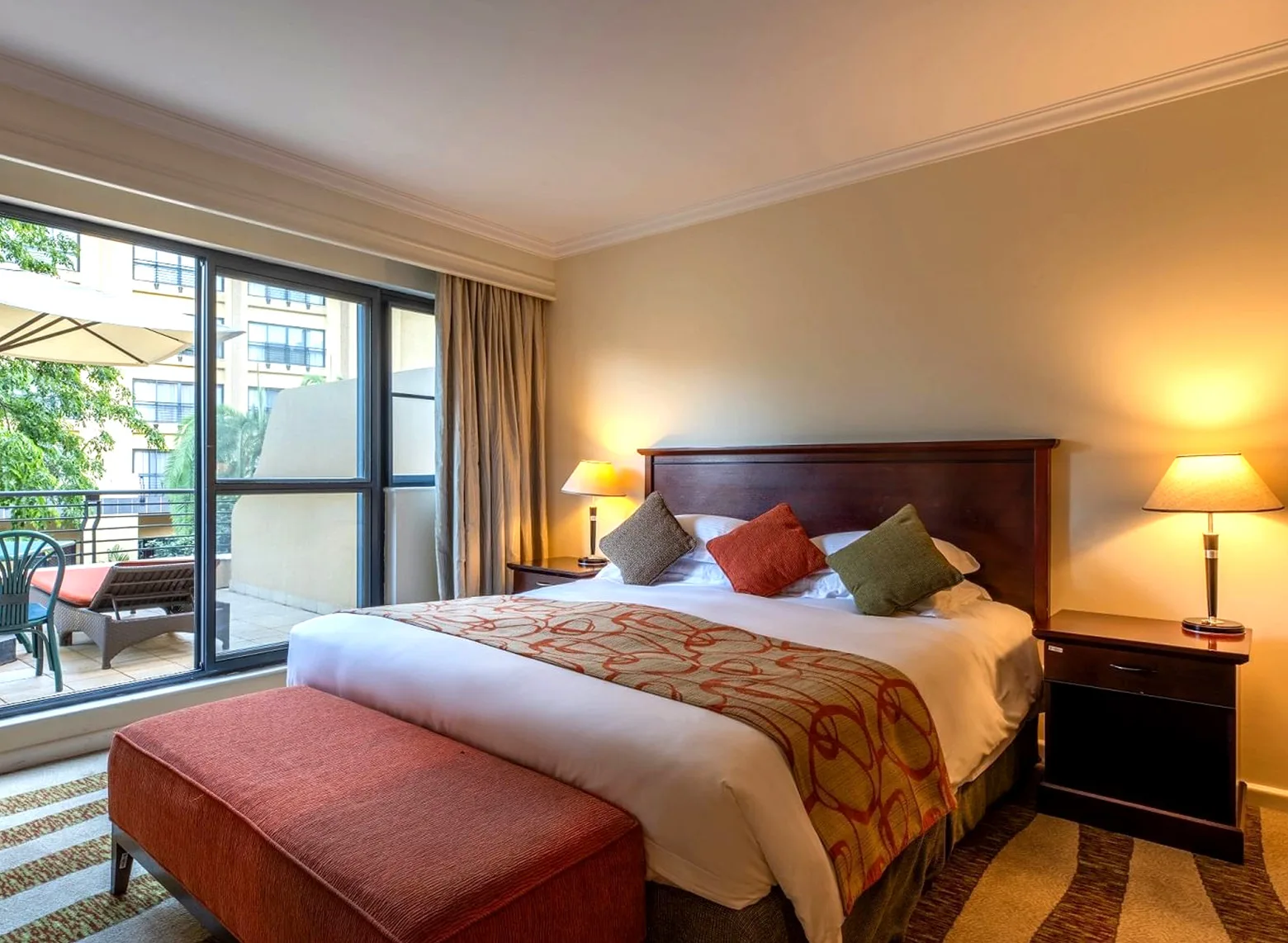 Guest room with a double bed and balcony doors at Kigali Serena Hotel