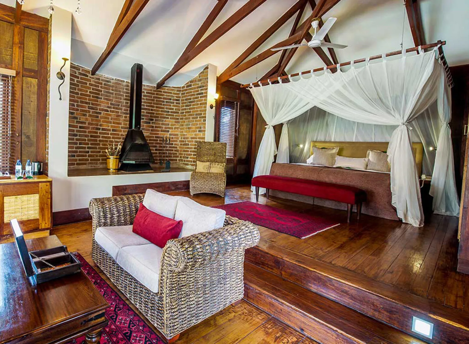 Guest suite with a four-poster bed, fireplace and wooden floors at Arusha Coffee Lodge