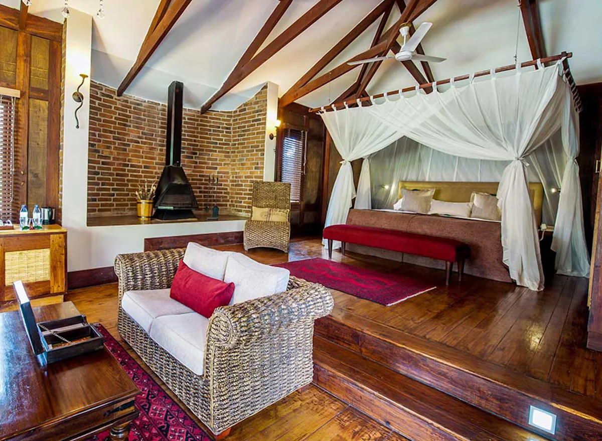 Guest suite with a four-poster bed, fireplace and wooden floors at Arusha Coffee Lodge
