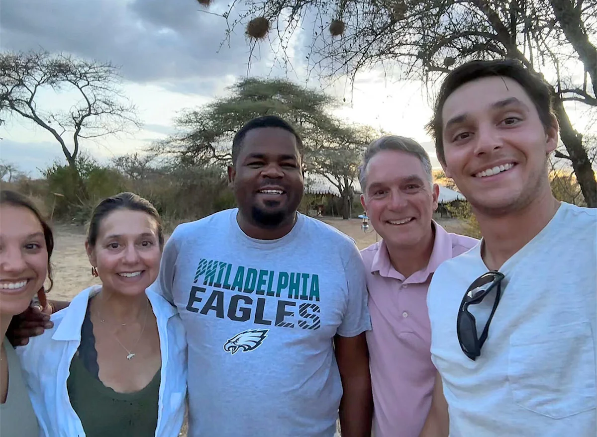 Group of travelers and a guide taking a smiling selfie at camp in the evening