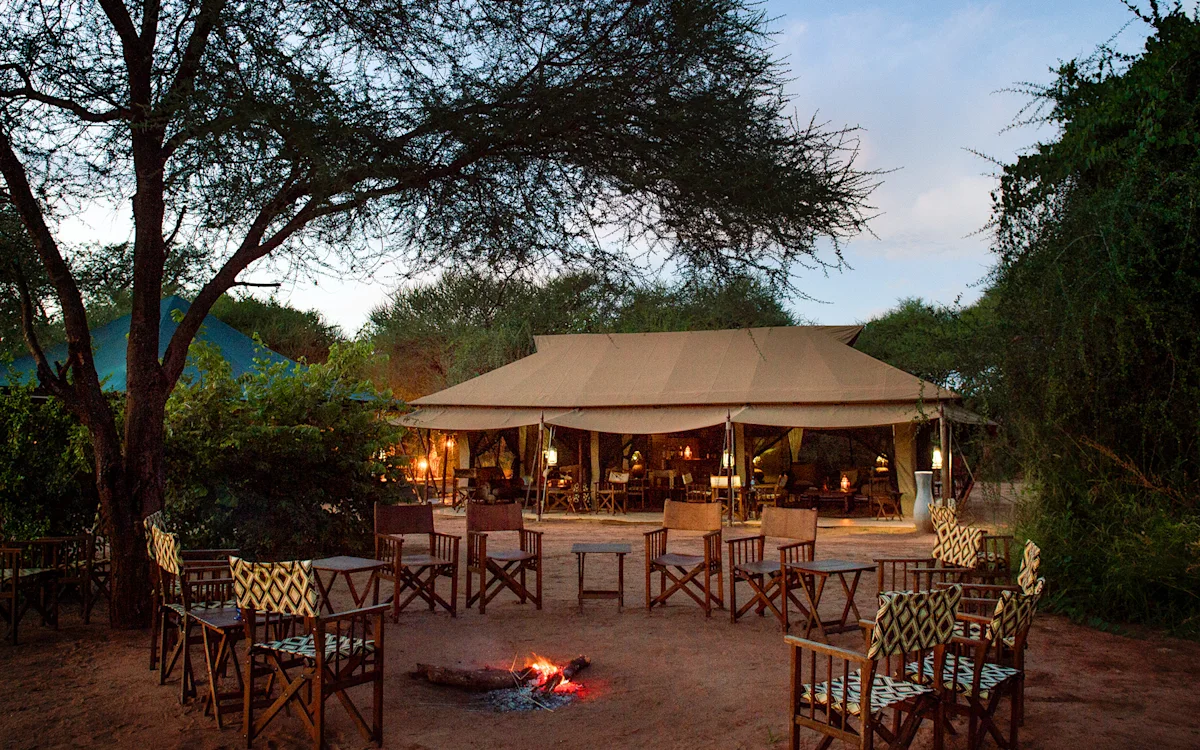 Campfire circle with director's chairs in front of the lounge tent at dusk at Tarangire Nyumba