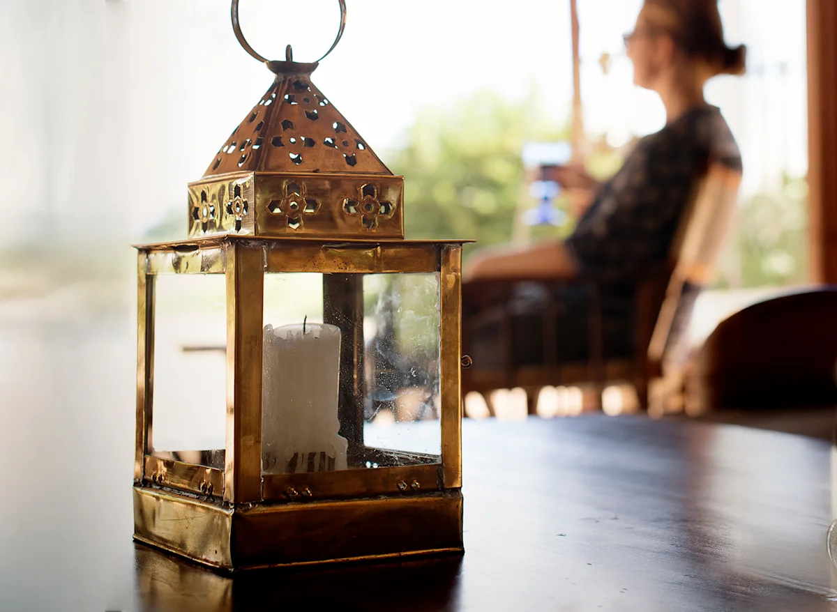 Brass lantern on a table with a guest relaxing in the background