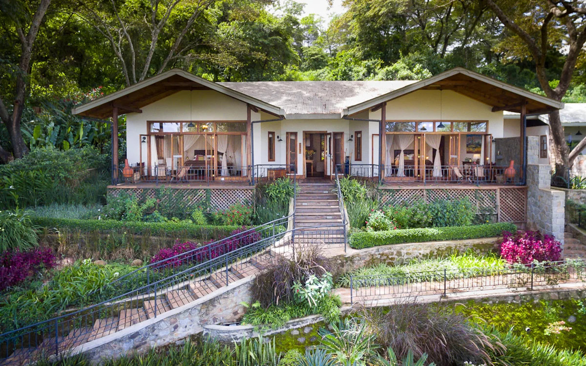 Bustani House with a veranda above terraced flower gardens at Gibb's Farm