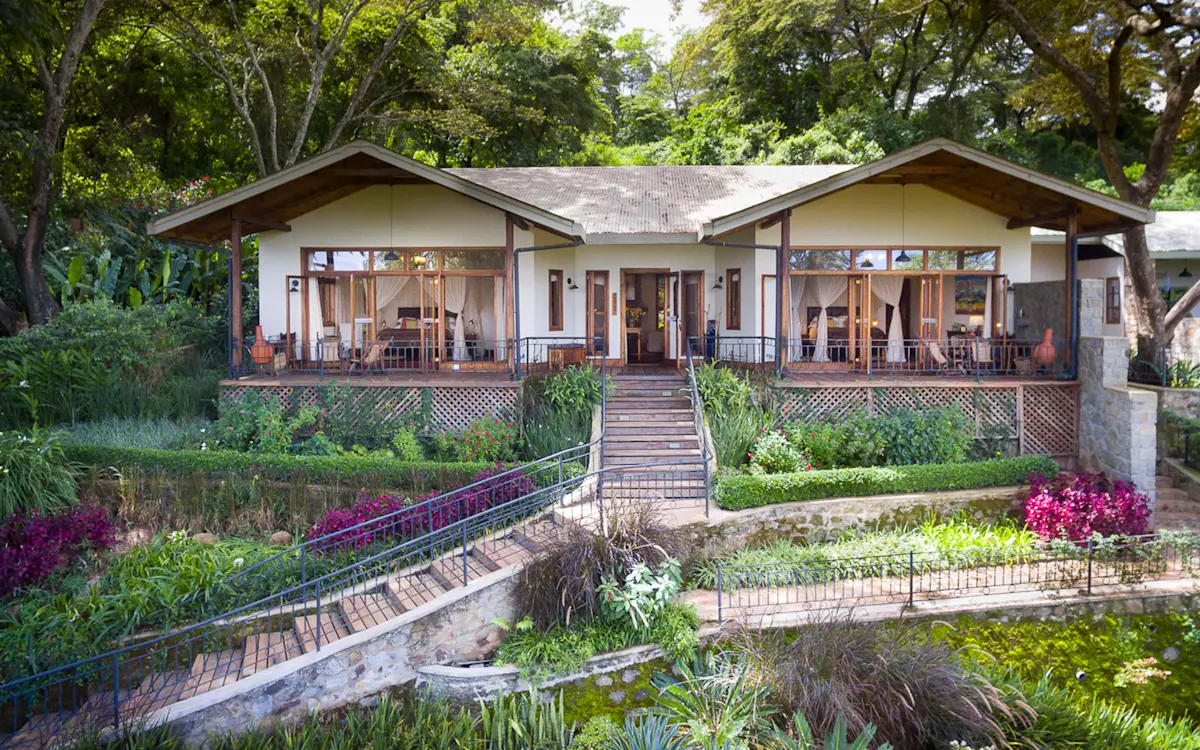 Bustani House with a veranda above terraced flower gardens at Gibb's Farm