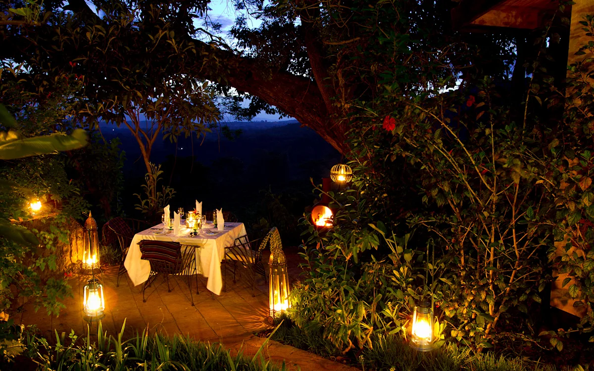 Lantern-lit dinner table for two in a garden at night at Gibb's Farm