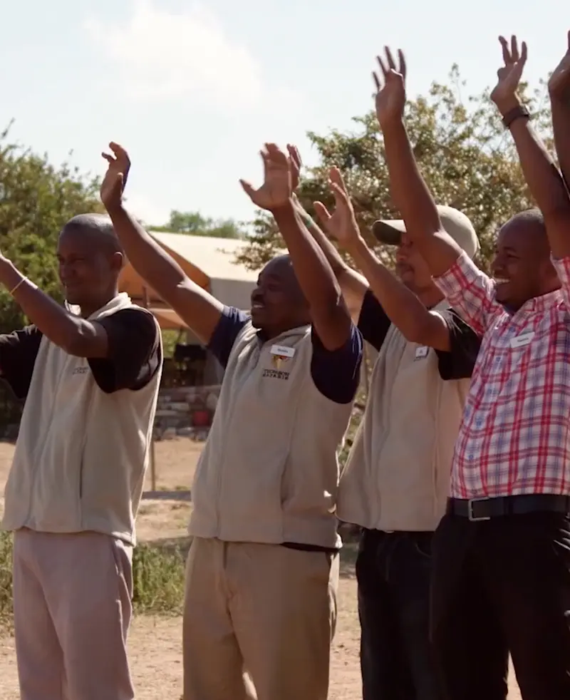 Nyumba camp staff raising their hands in a welcome