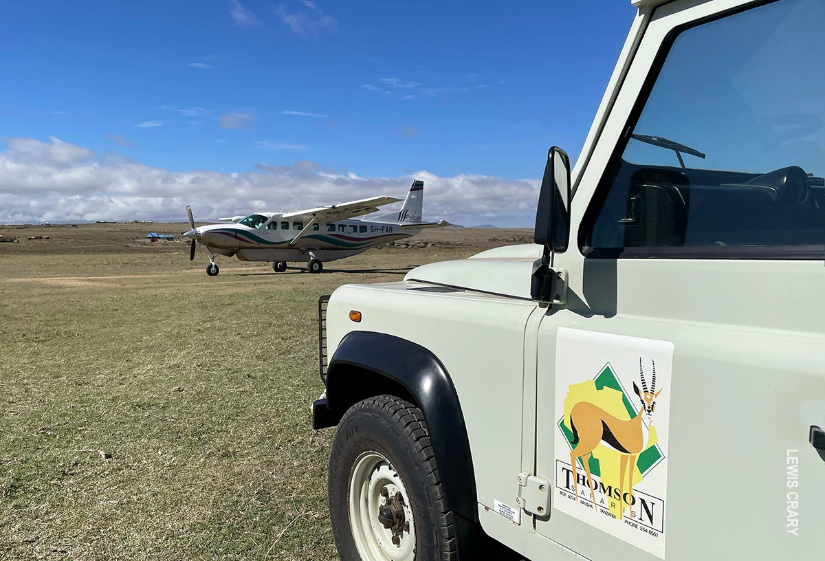Thomson Safaris vehicle parked on an airstrip near a small propeller plane