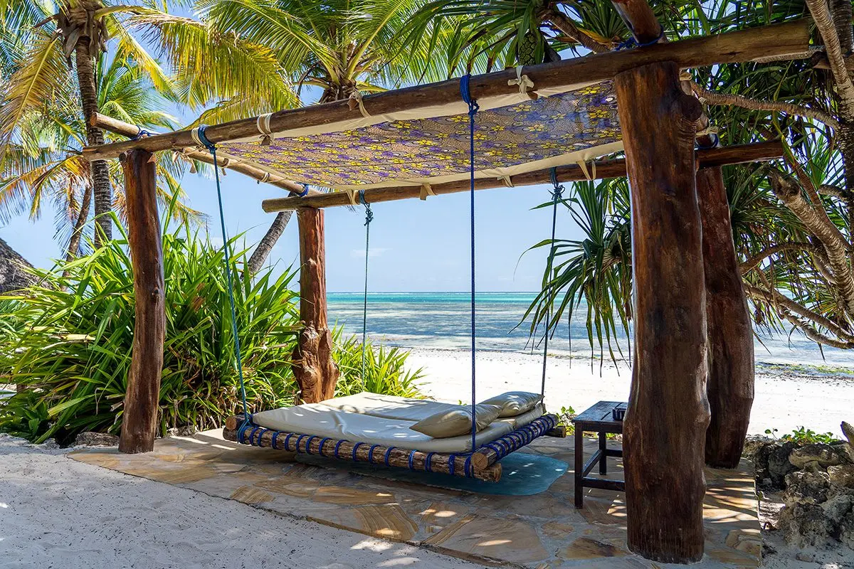 Hanging daybed under a thatched shelter on a Zanzibar beach