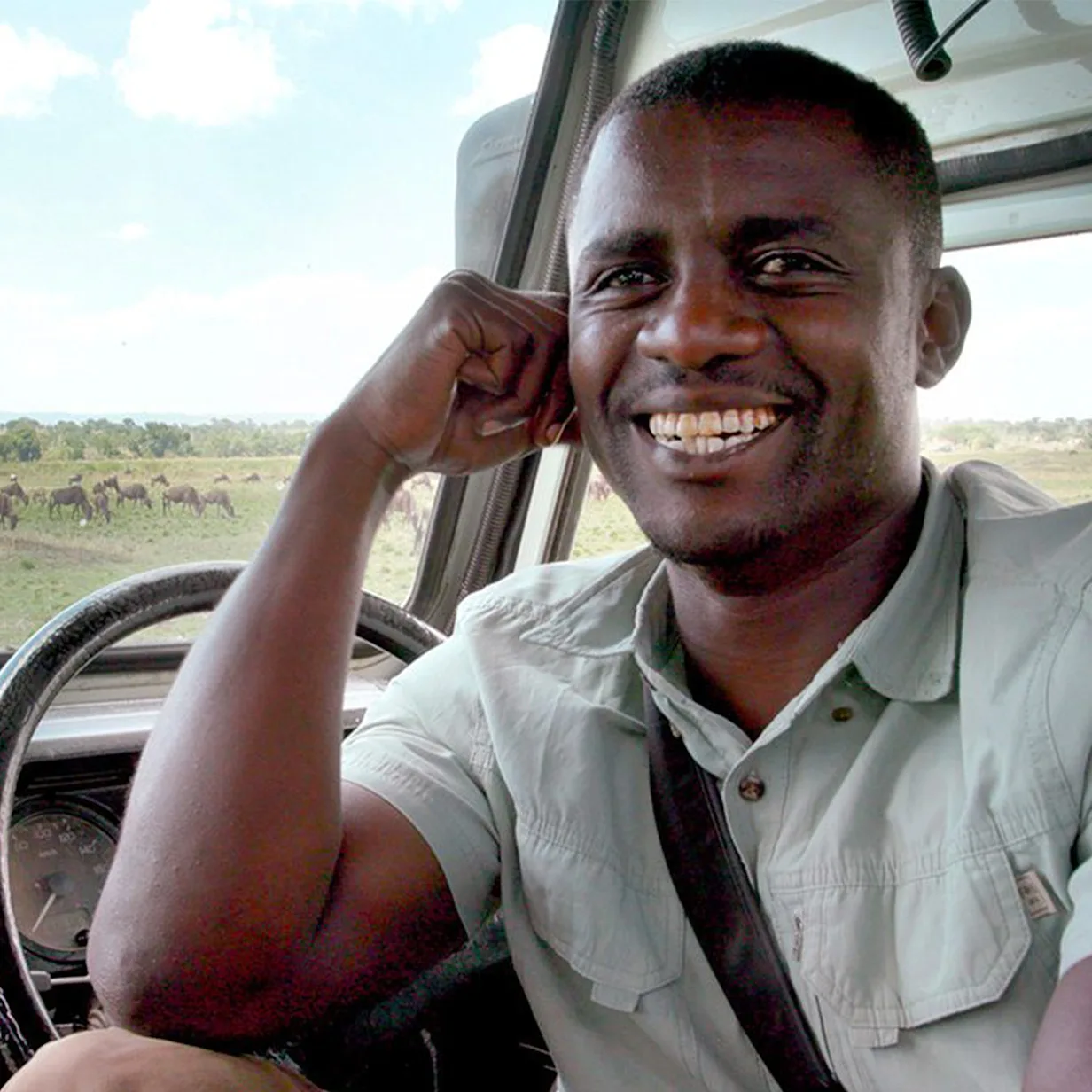Safari guide Seph smiling from the driver's seat of a safari vehicle