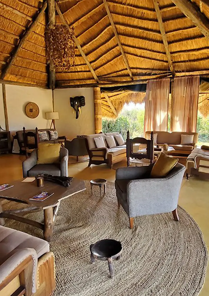 Thatched-roof lounge with armchairs, sofas, and a woven rug