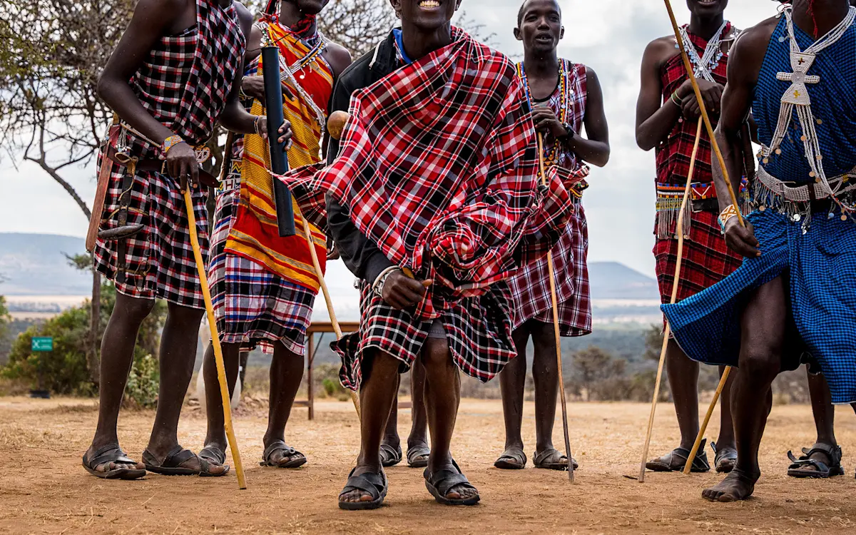 Maasai men in red and blue shukas holding walking sticks during a dance