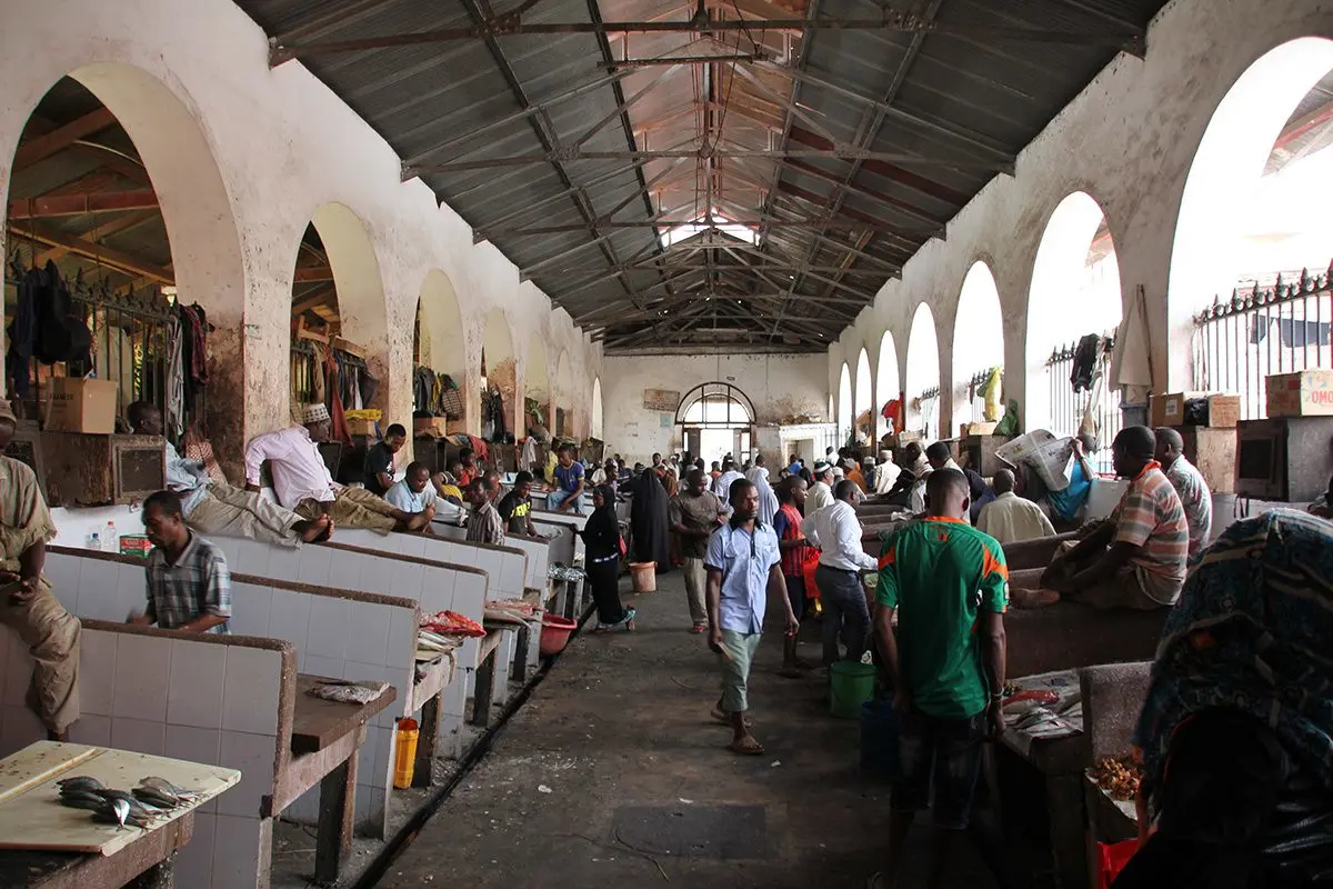 Shoppers and vendors in an arched, covered market hall in Zanzibar