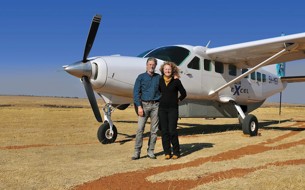 Founders Rick Thomson and Judi Wineland standing beside a small bush plane on a dirt airstrip