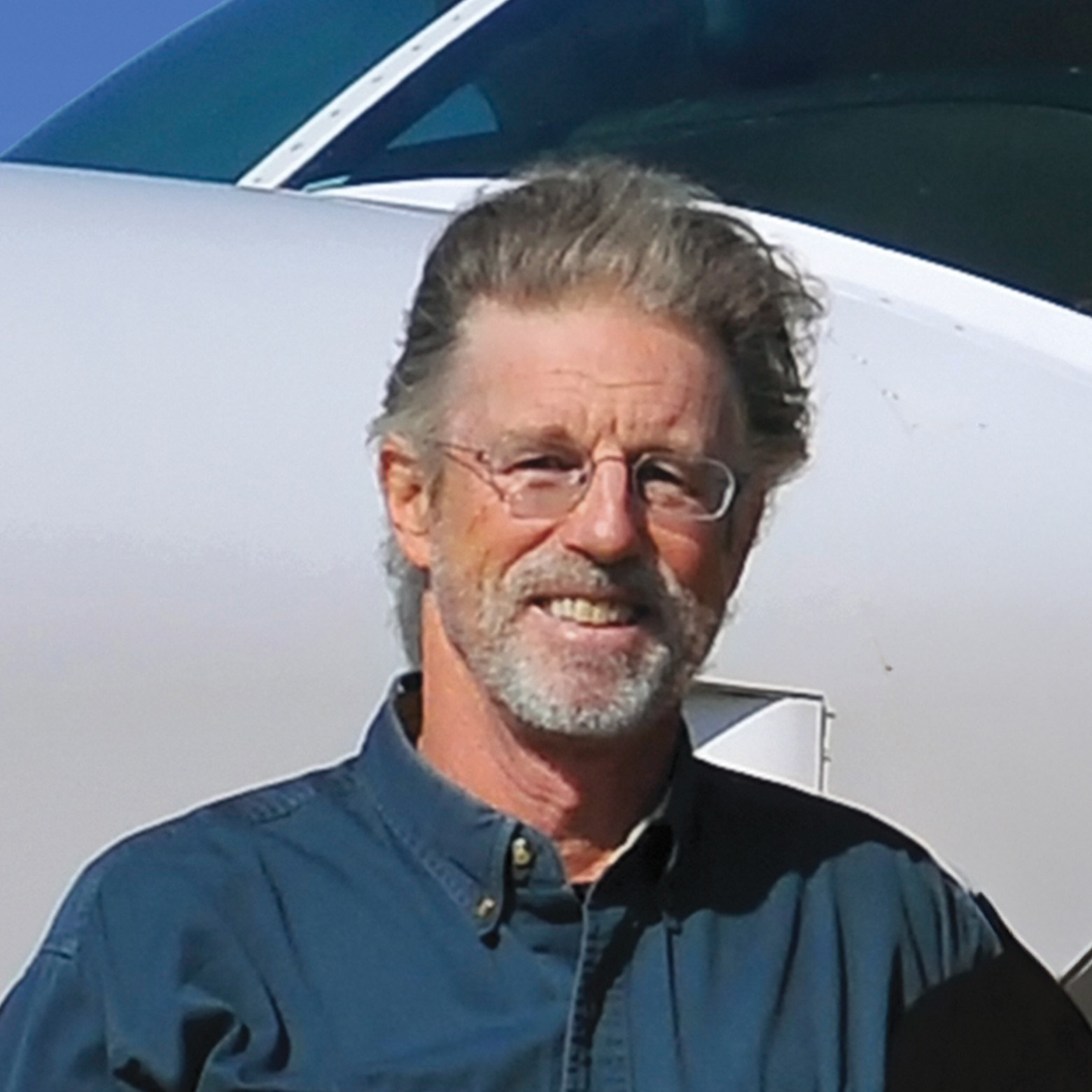 Portrait of Rick Thomson standing beside a small plane