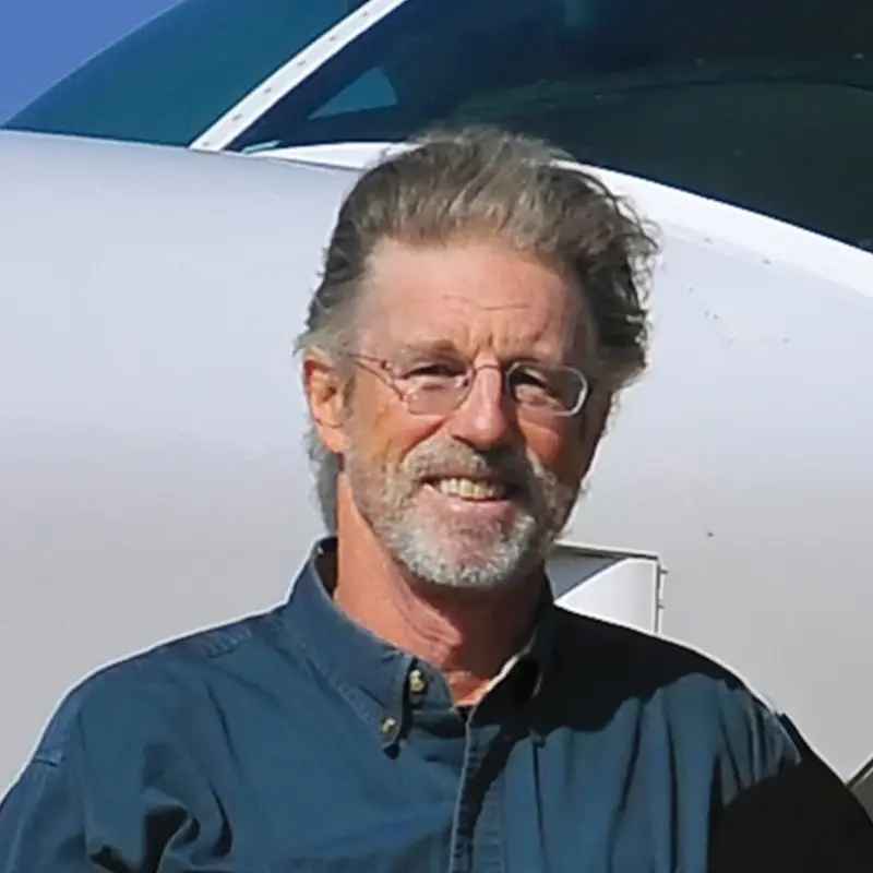 Portrait of Rick Thomson standing beside a small plane