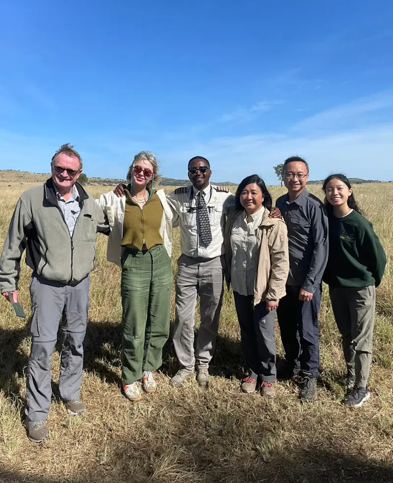 Group of travelers and their guide standing together on the grassy plains