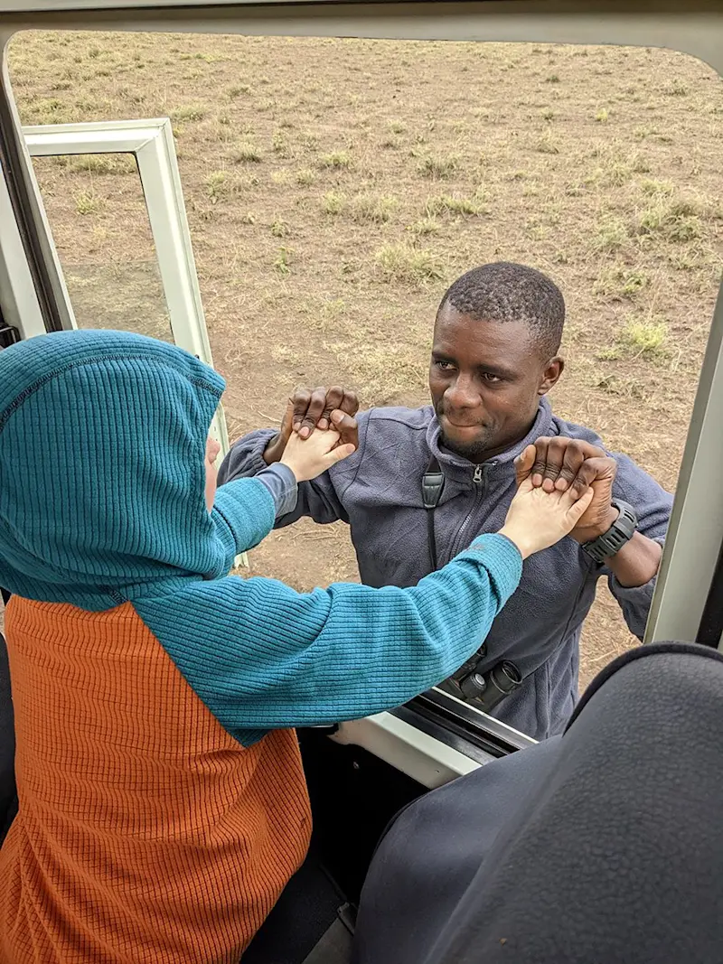 Child high-fiving a guide through the window of a safari vehicle