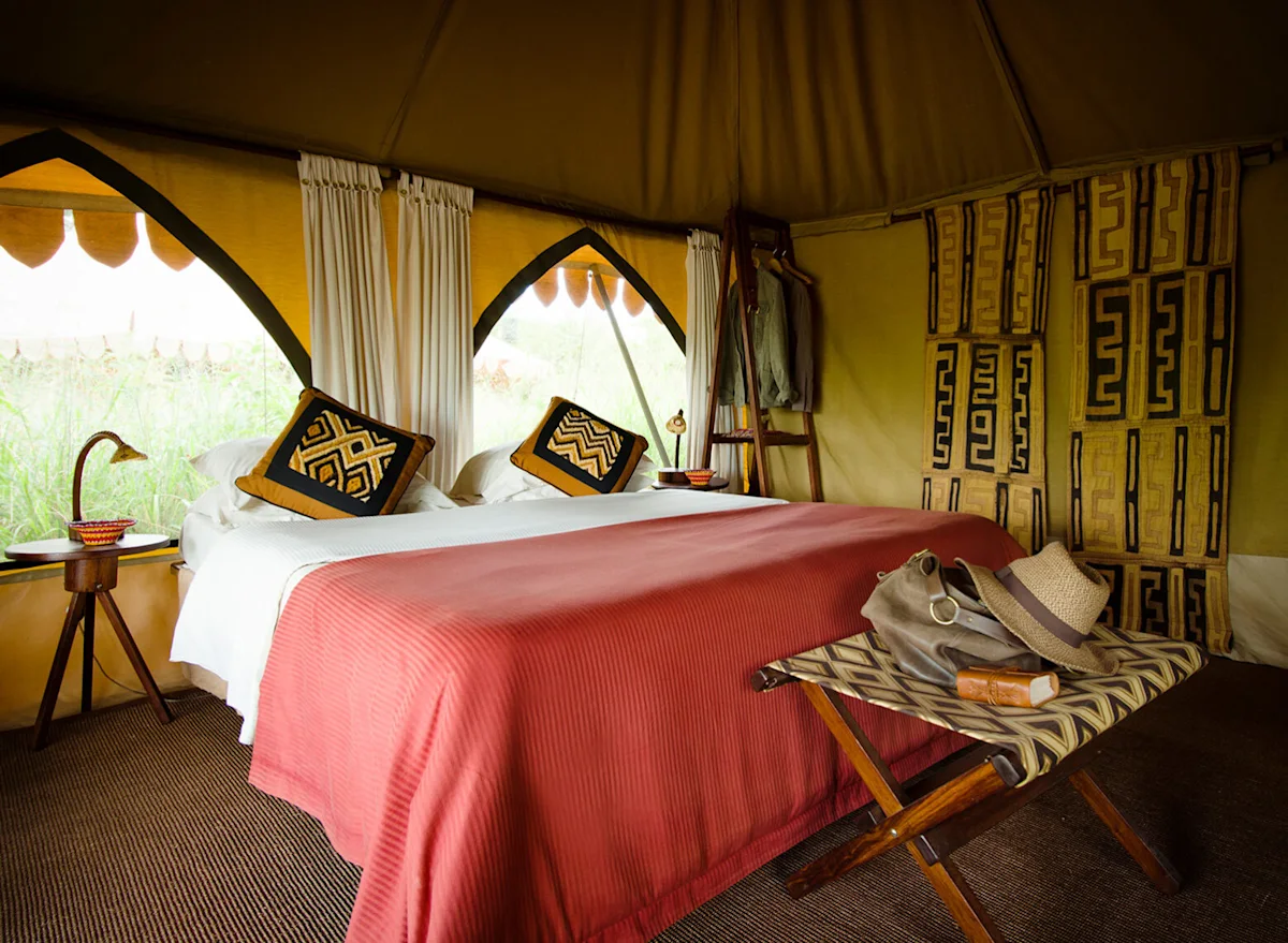 Guest tent interior with a bed and patterned textiles at Southern Serengeti Nyumba
