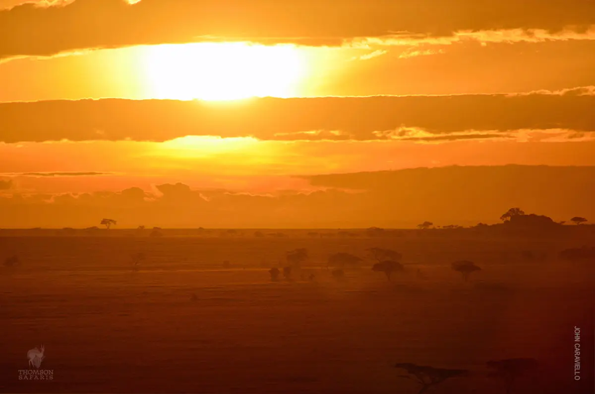 Sun rising over the Serengeti plains through layers of orange cloud