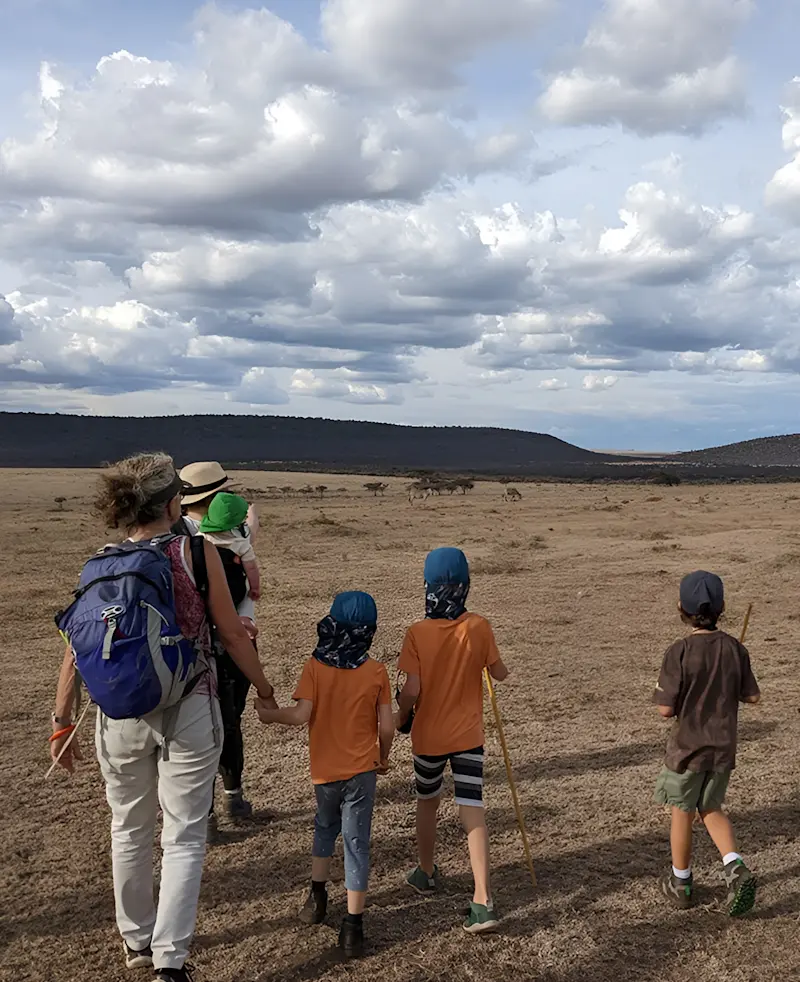 Adult walking with a group of children across an open plain