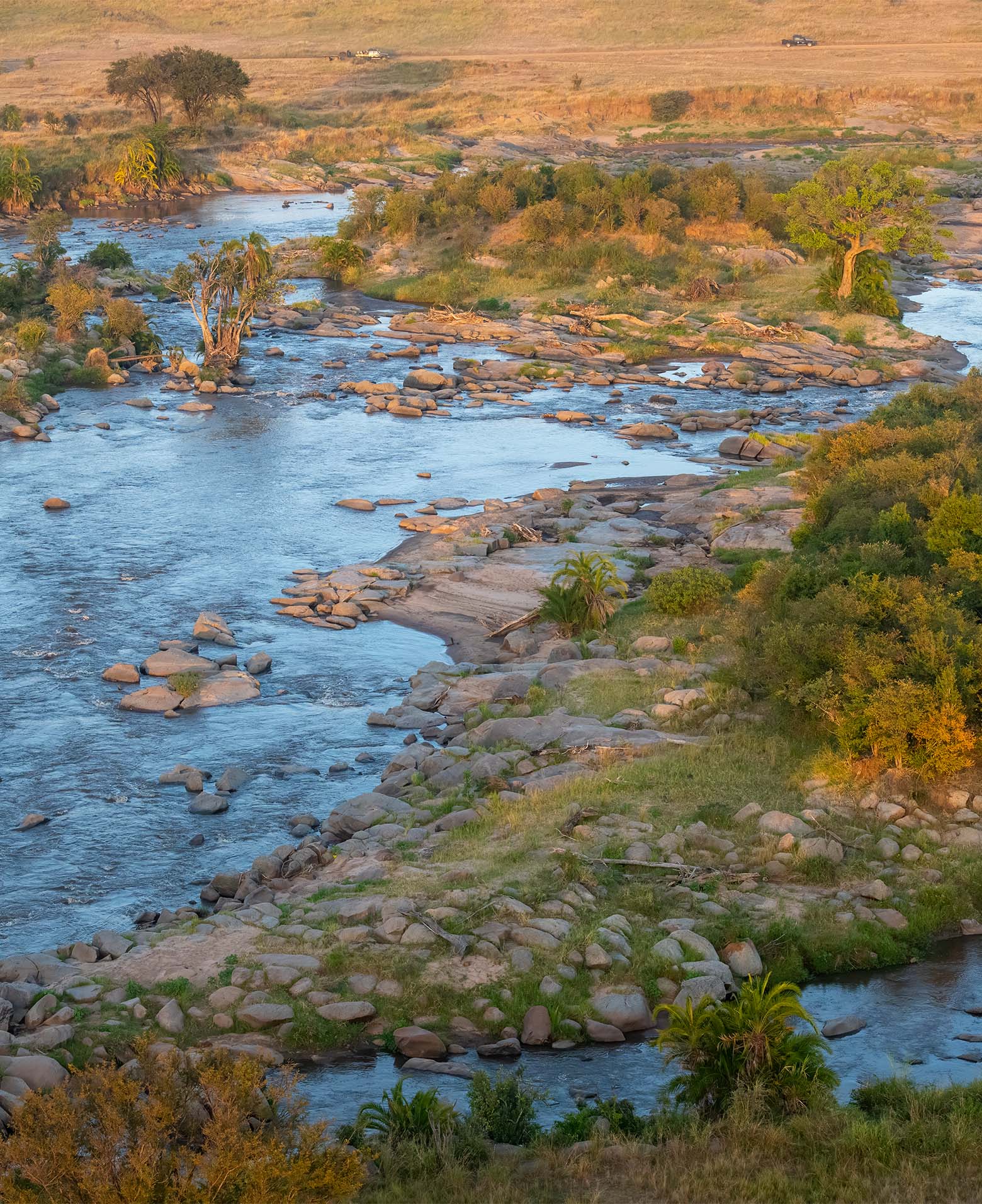 Rocky river winding through green bush in the Northern Serengeti