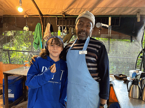 Smiling girl with a camp chef in an apron in the kitchen tent