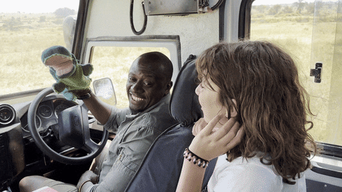 Safari guide with a hand puppet entertaining a young traveler in a safari vehicle