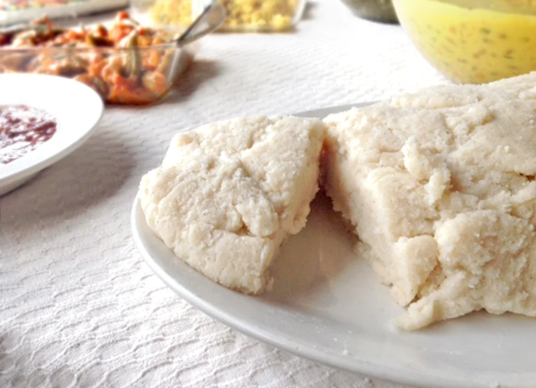 Plate of ugali beside bowls of other dishes