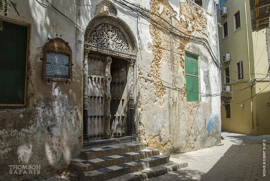 Ornately carved wooden door on a weathered old building in a Zanzibar street