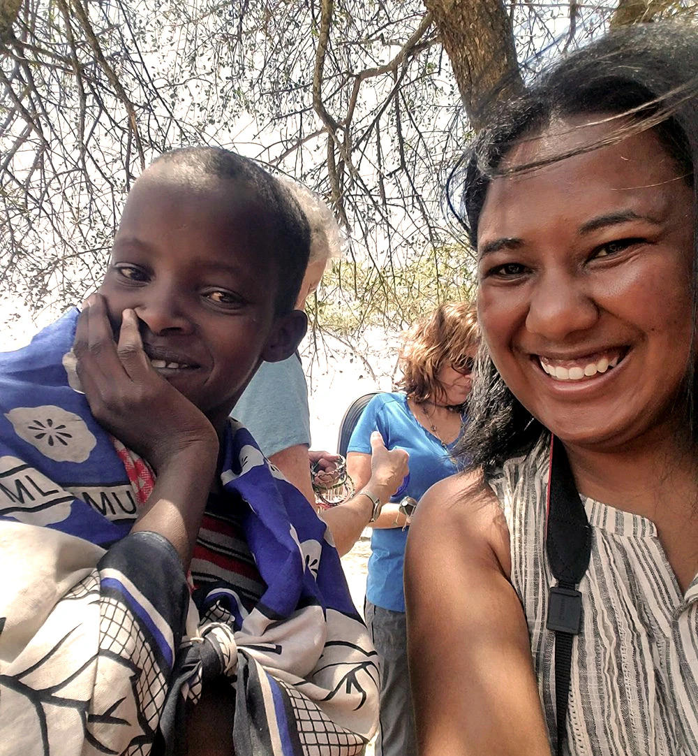 Smiling traveler taking a selfie with a Maasai child