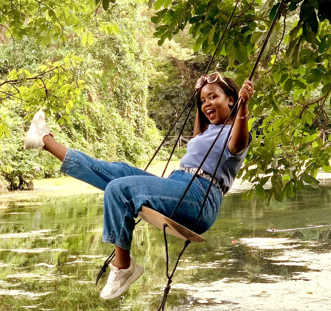 Mary Yamat laughing on a rope swing over a pond