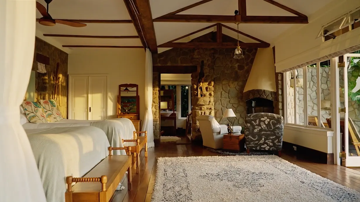 Cottage suite with twin beds, a stone fireplace and a sitting area at Gibb's Farm