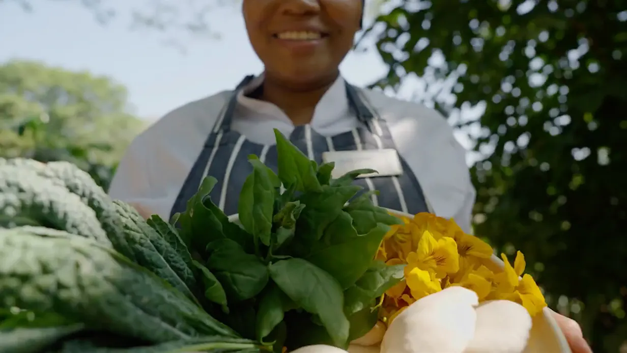 Chef holding a bundle of fresh greens and flowers from the garden at Gibb's Farm