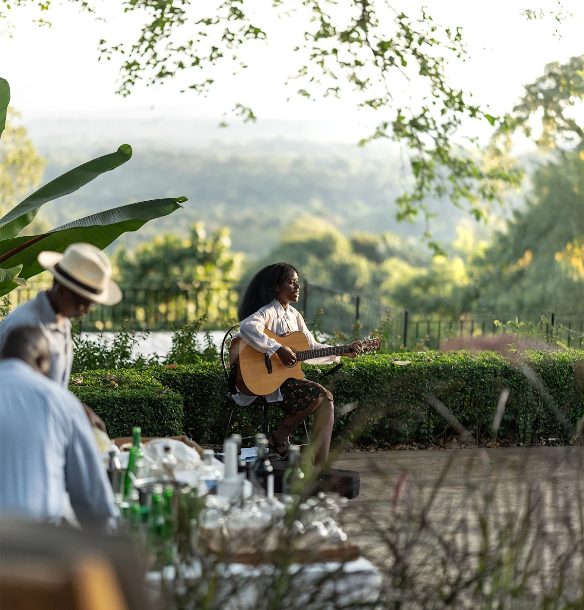 Musician playing guitar on a garden terrace as guests dine nearby at Gibb's Farm