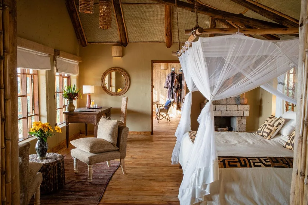 Bedroom with a four-poster bed, fireplace and writing desk at Virunga Lodge