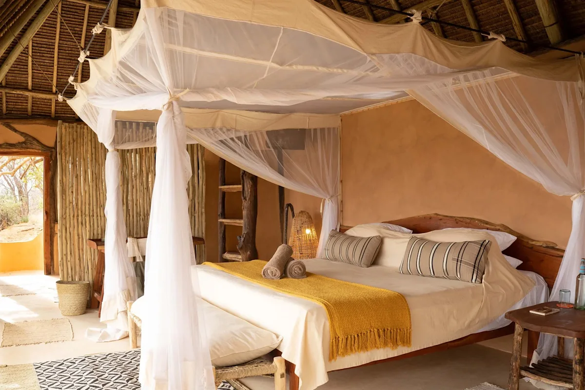 Four-poster bed with mosquito net under a thatched roof at Reteti House