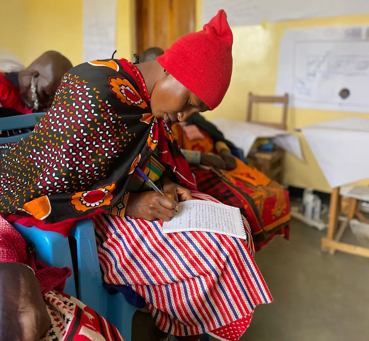 Maasai woman writing in a notebook during a classroom session