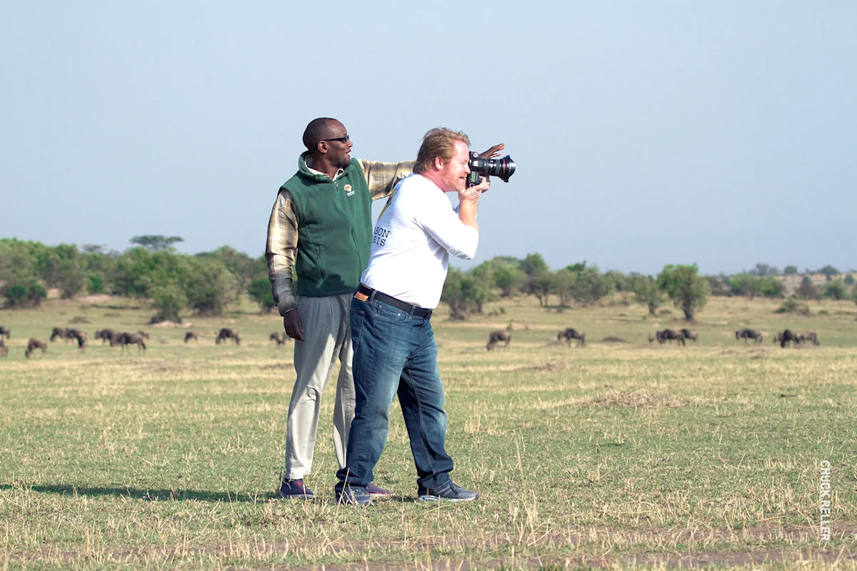 Guide pointing out wildlife to a photographer on the open plains