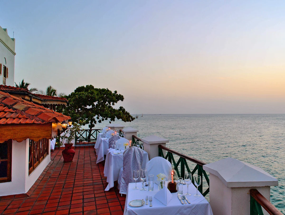 Seaside terrace with tables set for dinner at dusk at Zanzibar Serena Hotel