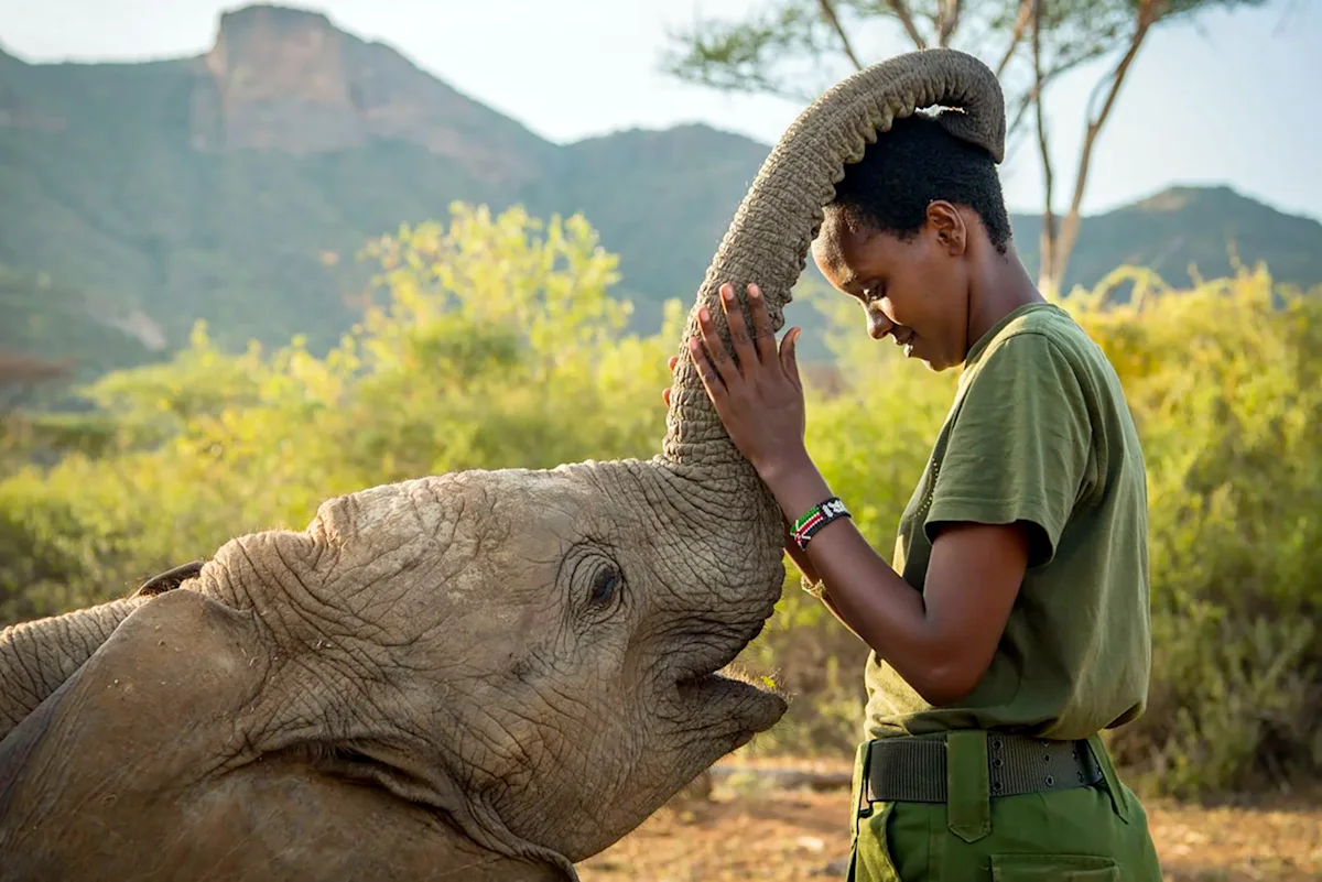 Keeper at Reteti Elephant Sanctuary leaning her head against a young elephant's trunk