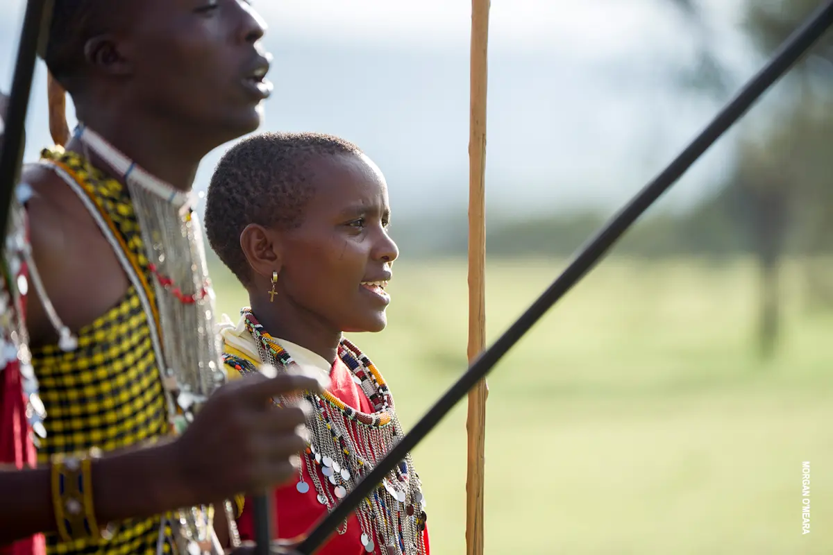 Maasai man and woman in beaded collars singing during a dance