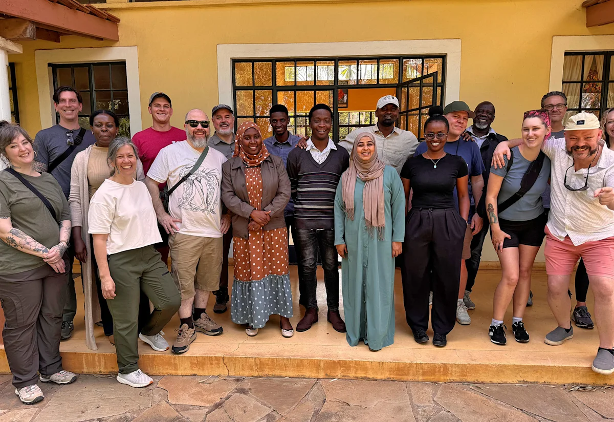 Group of travelers and Thomson staff posing on the porch of the Arusha office