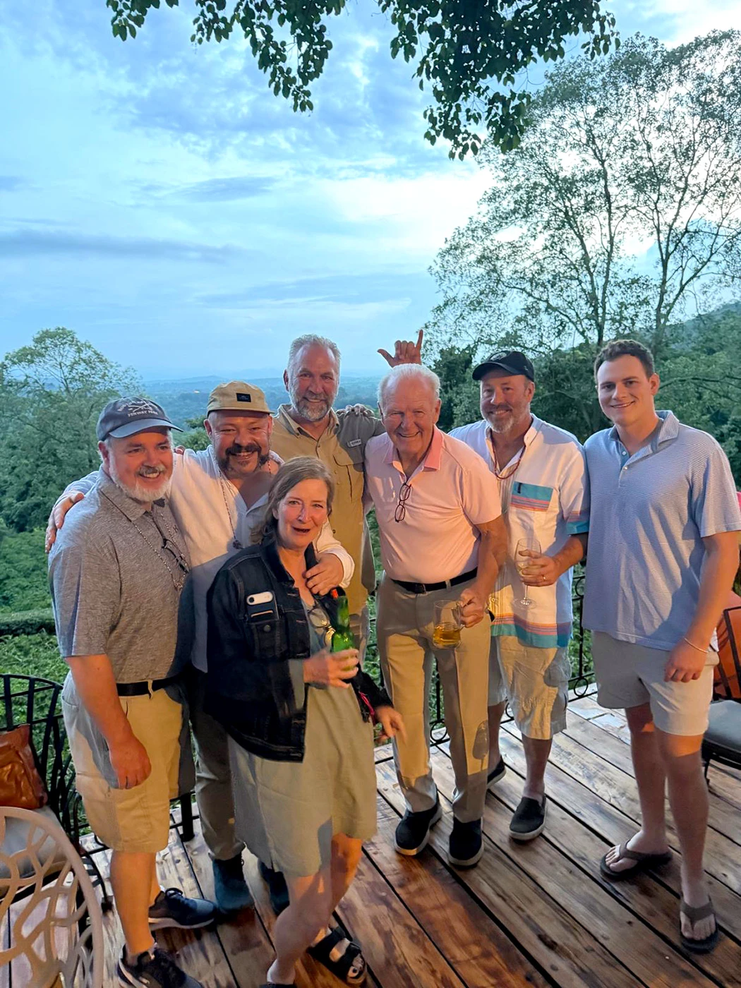 Group of travelers posing together on a lodge deck surrounded by trees